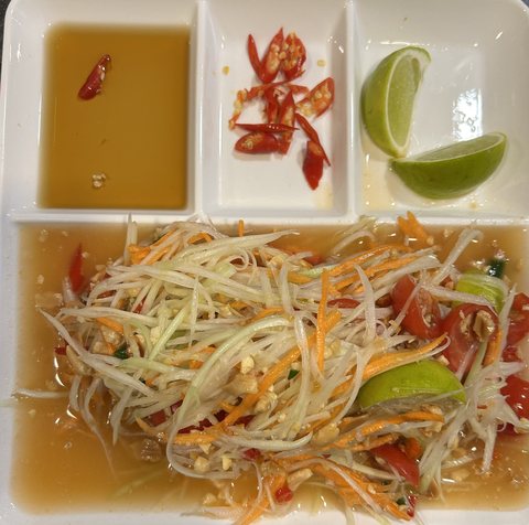 Som Tam: Salat aus grüner Papaya mit Tomaten, dazu Limette, Chili und Sauce in kleinen Schalen